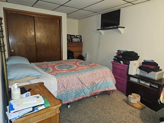 carpeted bedroom with a paneled ceiling and a closet