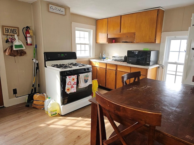 kitchen featuring light hardwood / wood-style flooring, range with gas cooktop, and white fridge