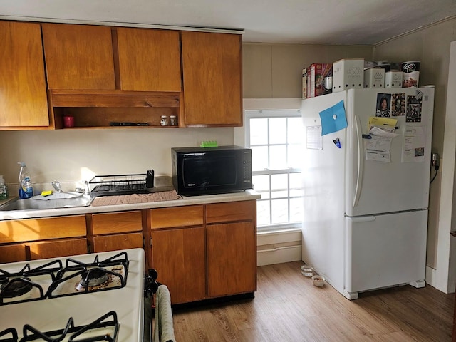 kitchen featuring plenty of natural light, white appliances, and light hardwood / wood-style flooring