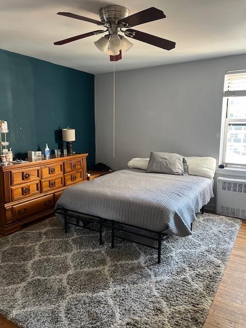 bedroom featuring hardwood / wood-style flooring, ceiling fan, and radiator