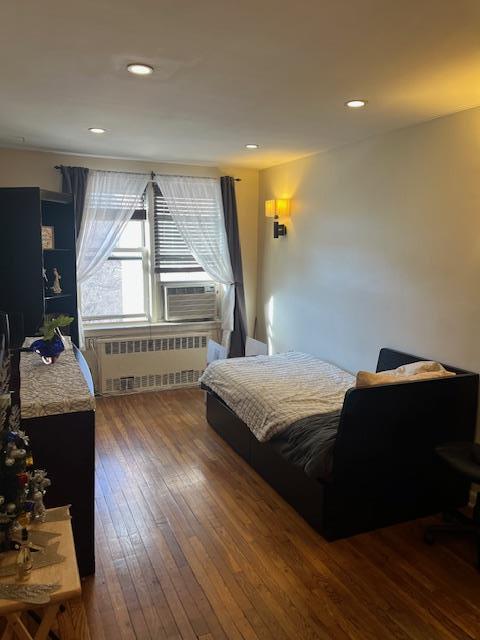 bedroom with cooling unit, dark wood-type flooring, and radiator heating unit