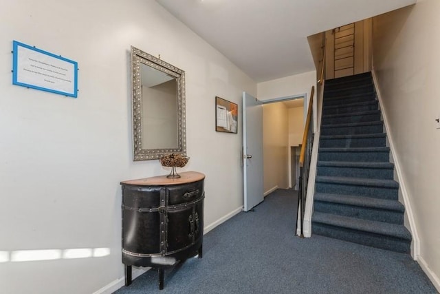 stairway featuring baseboards and carpet flooring