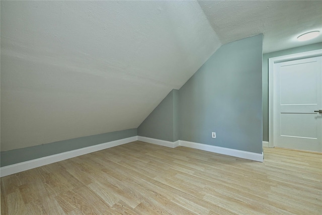 bonus room with lofted ceiling, light hardwood / wood-style flooring, and a textured ceiling