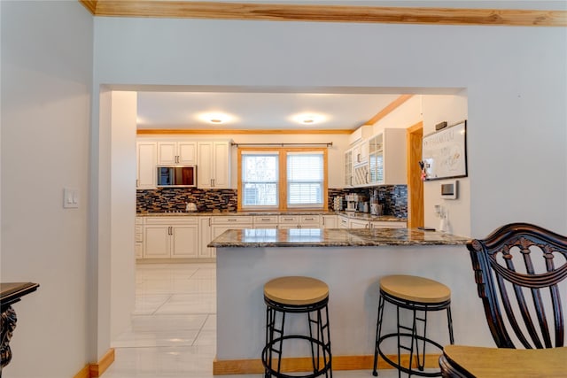 kitchen featuring ornamental molding, stone countertops, kitchen peninsula, and decorative backsplash