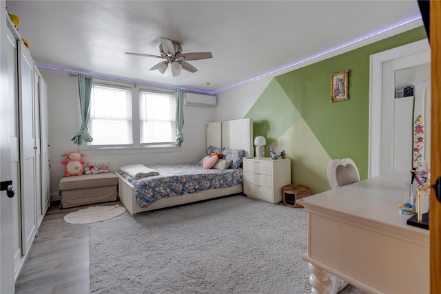 bedroom featuring ceiling fan, ornamental molding, light wood-type flooring, and an AC wall unit