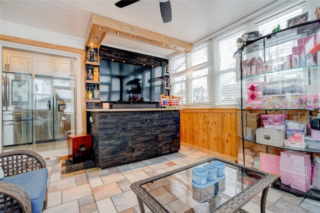 interior space featuring light brown cabinetry, wooden walls, stainless steel refrigerator, and ceiling fan