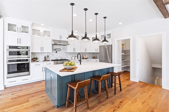 kitchen with light countertops, tasteful backsplash, white cabinetry, and under cabinet range hood