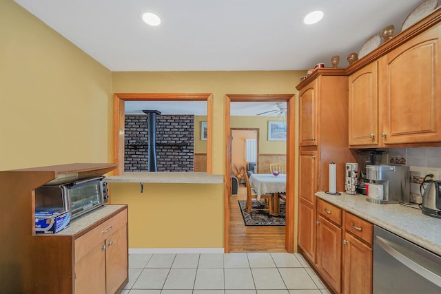 kitchen featuring tasteful backsplash, a wood stove, stainless steel dishwasher, and light tile patterned flooring