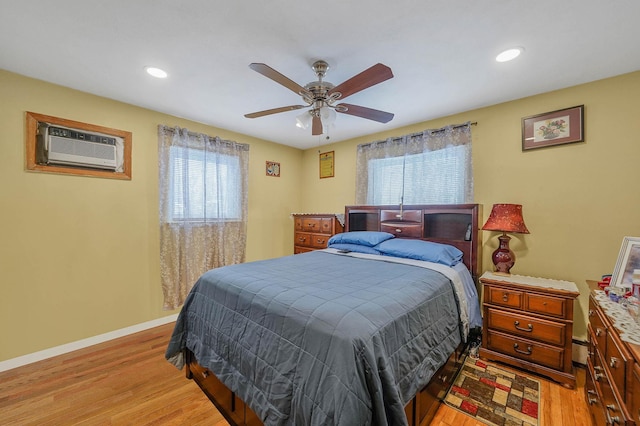 bedroom featuring ceiling fan, light hardwood / wood-style floors, and a wall mounted AC