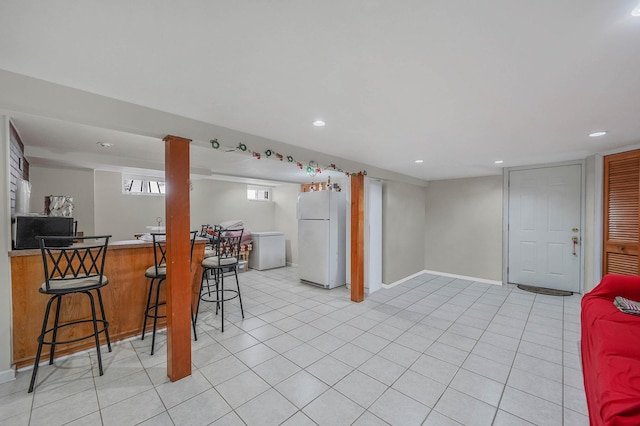 interior space featuring a breakfast bar, light tile patterned floors, white refrigerator, fridge, and kitchen peninsula