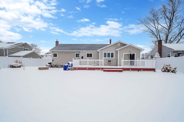 snow covered back of property with a wooden deck