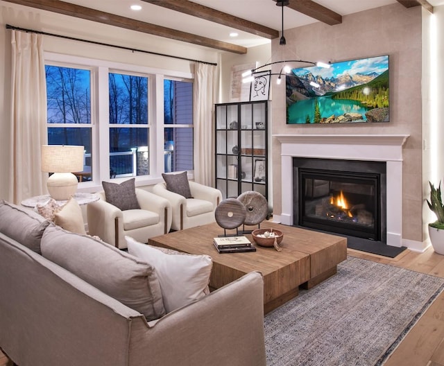 living room with recessed lighting, a glass covered fireplace, wood finished floors, beamed ceiling, and baseboards