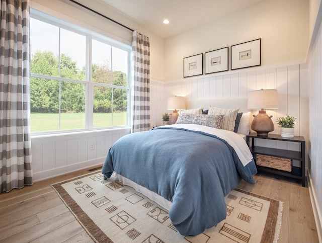 bedroom featuring light wood finished floors, a wainscoted wall, and recessed lighting