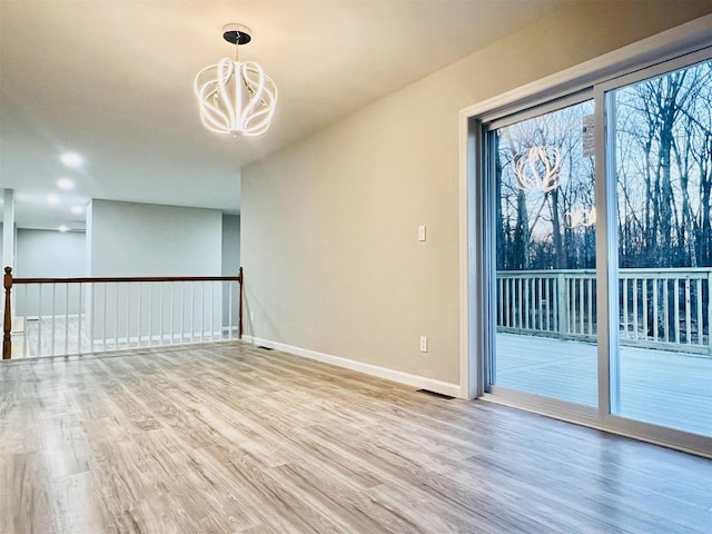 empty room with a chandelier and light wood-type flooring