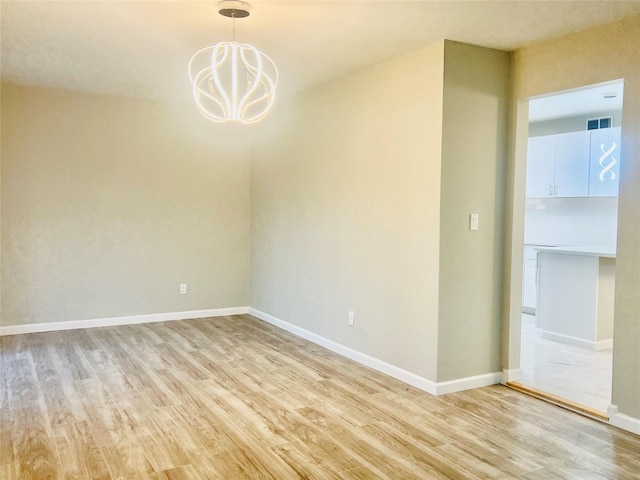 unfurnished room with a chandelier and light hardwood / wood-style flooring