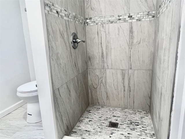 bathroom featuring a tile shower and toilet