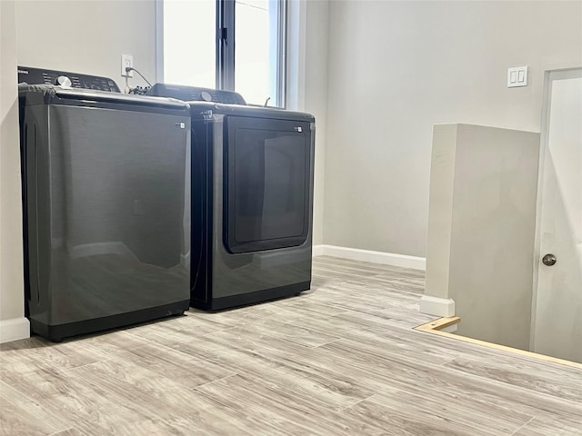 laundry room with washing machine and clothes dryer and light wood-type flooring