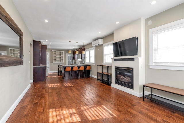 unfurnished living room featuring dark hardwood / wood-style floors and an AC wall unit