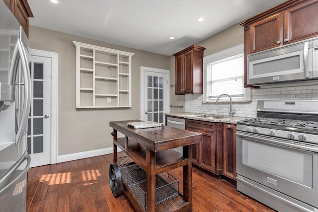 kitchen with stainless steel appliances, sink, dark wood-type flooring, and light stone counters