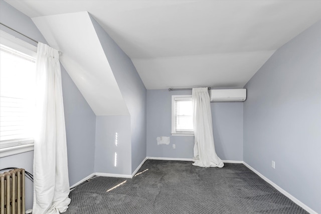 additional living space featuring dark colored carpet, radiator heating unit, vaulted ceiling, and an AC wall unit