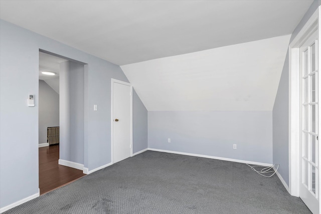 additional living space with vaulted ceiling and dark colored carpet