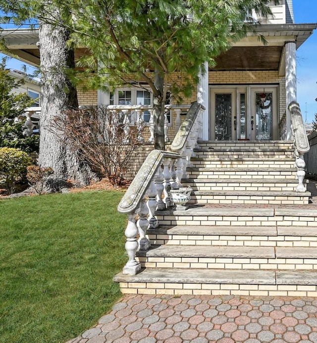 view of exterior entry featuring a yard and brick siding