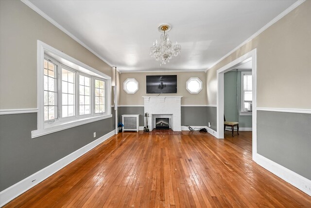 unfurnished living room with crown molding, a fireplace, baseboards, and wood finished floors