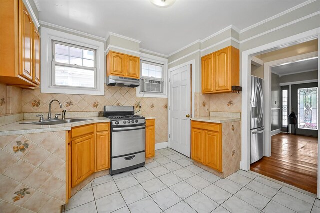 kitchen with a sink, stainless steel appliances, light countertops, and under cabinet range hood