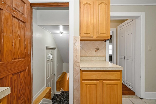 kitchen with light tile patterned floors, tasteful backsplash, light brown cabinets, and light countertops