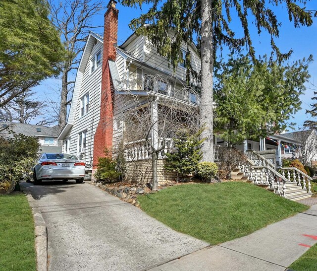 view of property exterior featuring stairway, a chimney, and a lawn