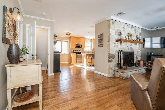 living room with crown molding, a fireplace, and light hardwood / wood-style floors