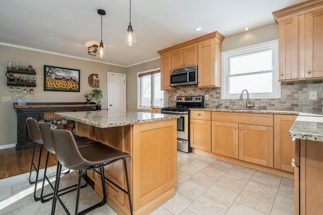 kitchen with a kitchen island, appliances with stainless steel finishes, tasteful backsplash, sink, and hanging light fixtures