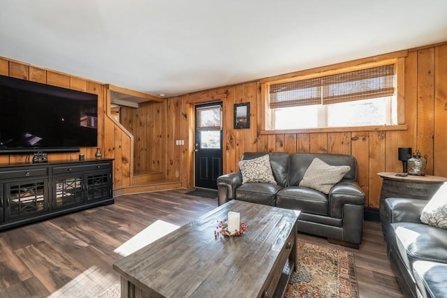 living room with dark hardwood / wood-style flooring and wooden walls