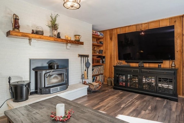 living room with wooden walls, dark hardwood / wood-style floors, and a wood stove