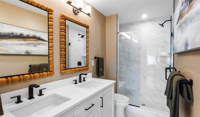 full bathroom with toilet, double vanity, a sink, and a marble finish shower