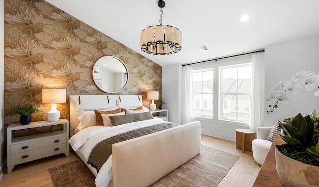 bedroom with light wood-style floors, visible vents, a chandelier, and wallpapered walls