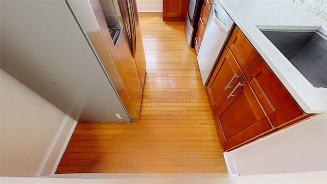 interior space featuring sink, stainless steel dishwasher, light stone countertops, and light wood-type flooring