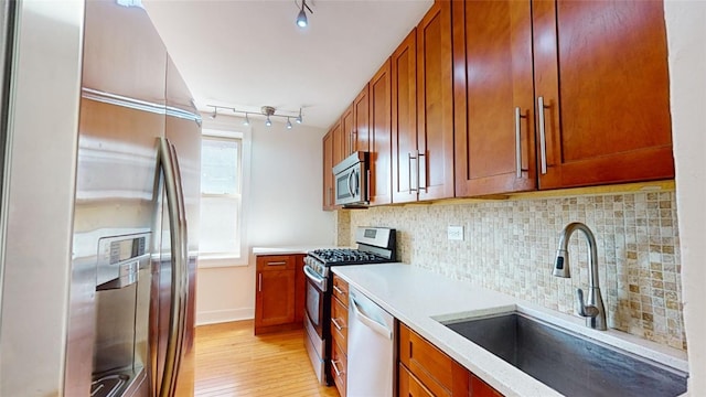 kitchen with sink, backsplash, light hardwood / wood-style floors, and appliances with stainless steel finishes