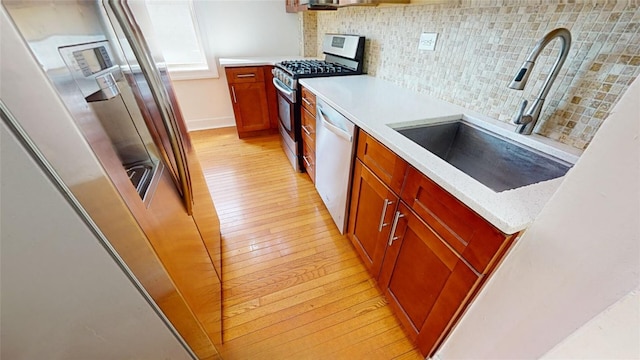 kitchen with sink, backsplash, stainless steel appliances, and light hardwood / wood-style floors