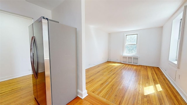 empty room with a barn door, radiator heating unit, and light hardwood / wood-style flooring