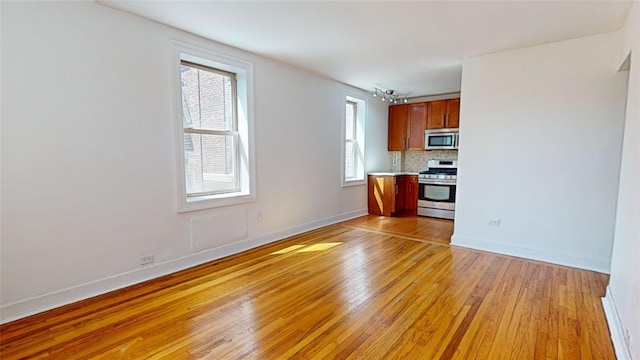 interior space with appliances with stainless steel finishes, decorative backsplash, and light hardwood / wood-style flooring