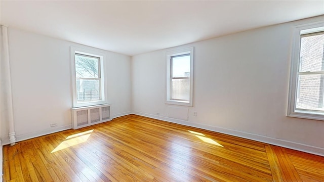 unfurnished room featuring radiator heating unit and light hardwood / wood-style floors