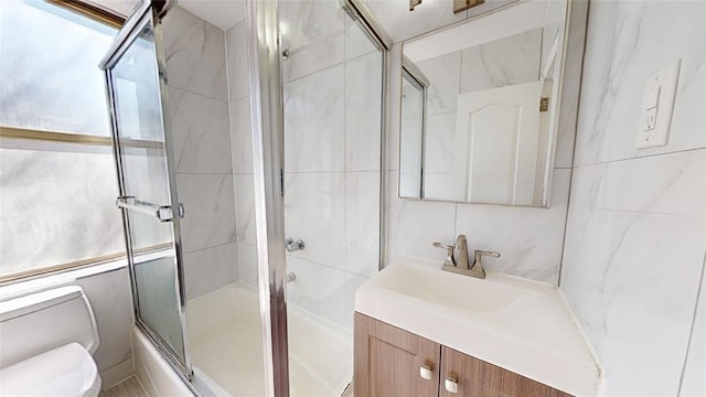 full bathroom featuring enclosed tub / shower combo, vanity, toilet, and tile walls