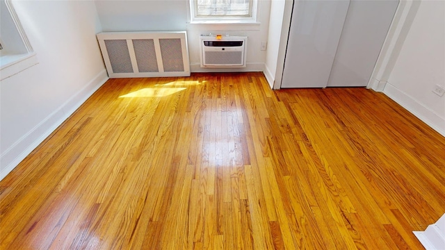 interior space featuring radiator, light hardwood / wood-style flooring, and a wall unit AC