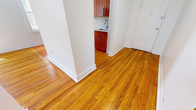 hall with sink and light wood-type flooring