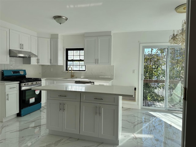 kitchen with white cabinets, sink, stainless steel gas range, and decorative backsplash