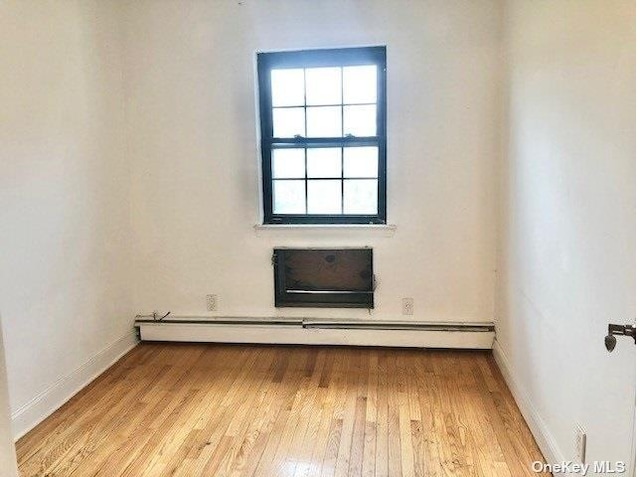 spare room with baseboard heating and light hardwood / wood-style floors