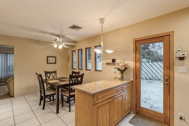 kitchen with light stone countertops, light tile patterned floors, ceiling fan, and decorative light fixtures