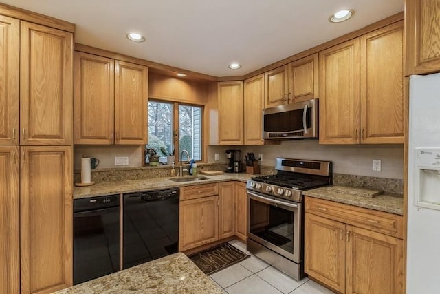 kitchen with light stone counters, sink, light tile patterned floors, and appliances with stainless steel finishes