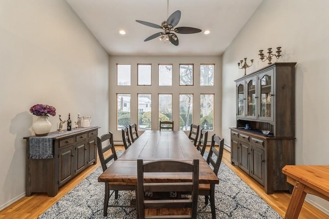 dining space featuring light hardwood / wood-style flooring, ceiling fan, and a high ceiling